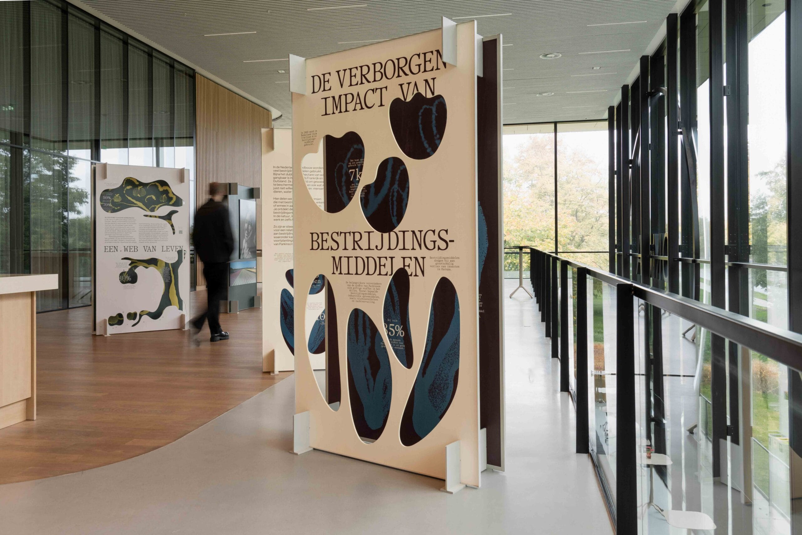 Tentoonstelling The Hidden Impact of Pesticides – reizende expositie over pesticiden en hun invloed op mens, dier en milieu, met dubbelzijdige panelen en organische vormen, gebouwd door Studio Onder Constructie.
